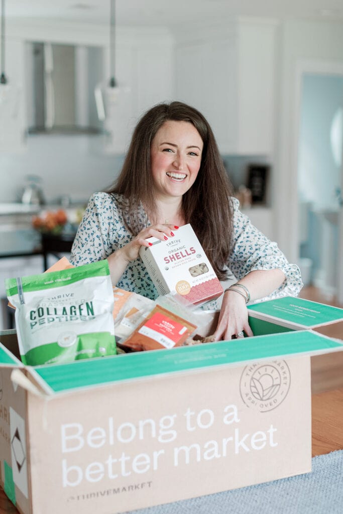 An honest thrive market review - a girl taking out food from the box of thrive market goods